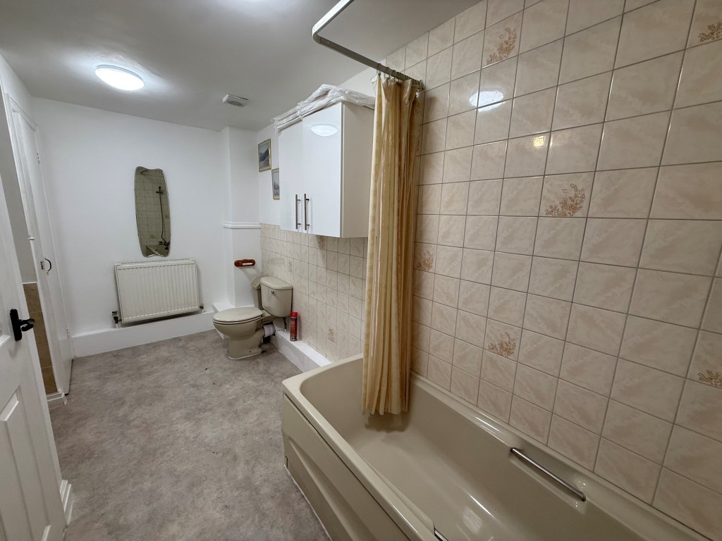 Lot: 6 - INVESTMENT OPPORTUNITY IN TOWN CENTRE LOCATION WITH OFF ROAD PARKING - Ground floor tiled bathroom with bath, sink and WC